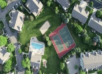 A bird 's eye view of a tennis court in the middle of a neighborhood.